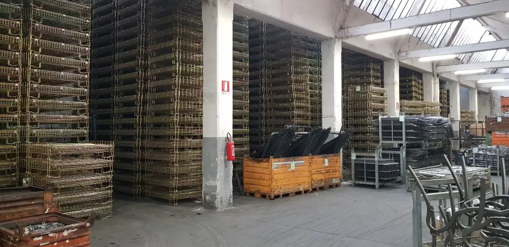 Zusammengeklappte verzinkte Drahtgitterboxen in großen Stapeln innerhalb einer Lagerhalle